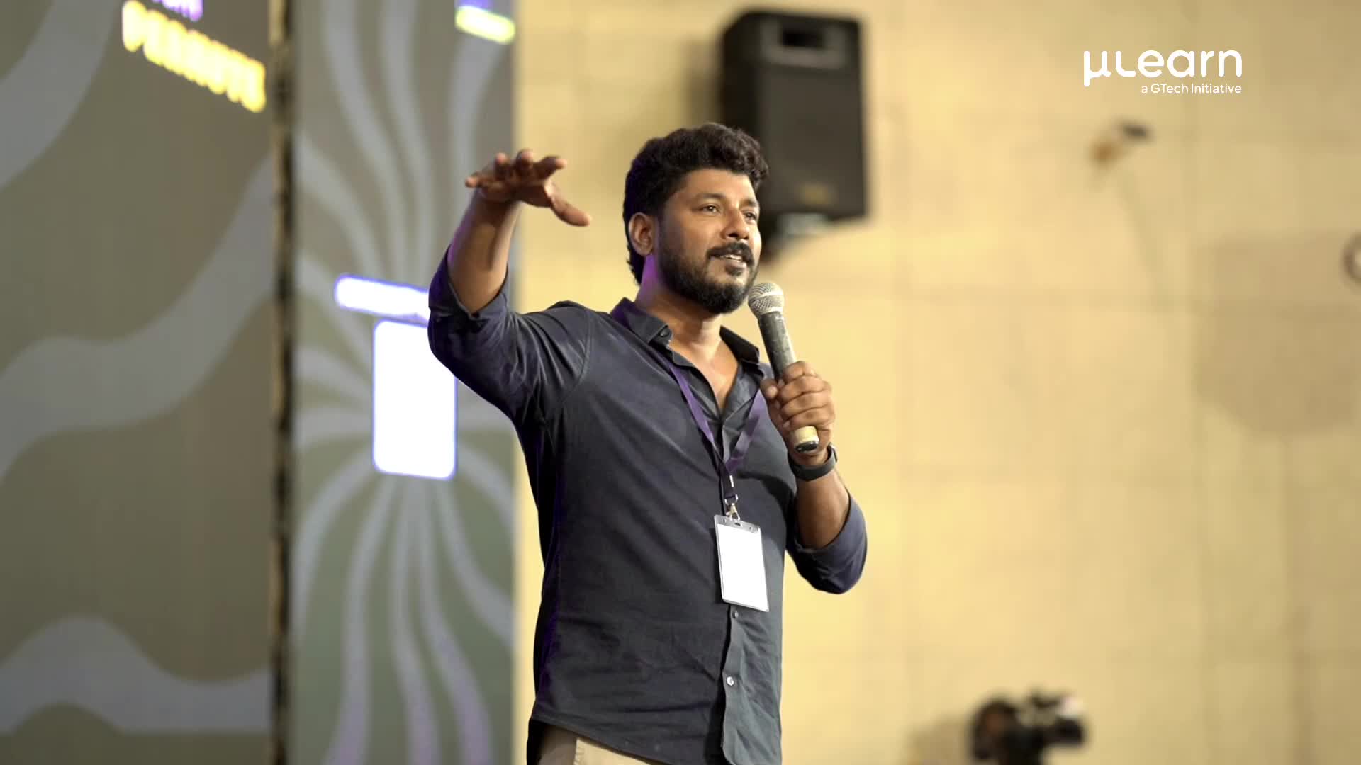 Speaker on stage mid-gesture at a MuLearn Foundation event