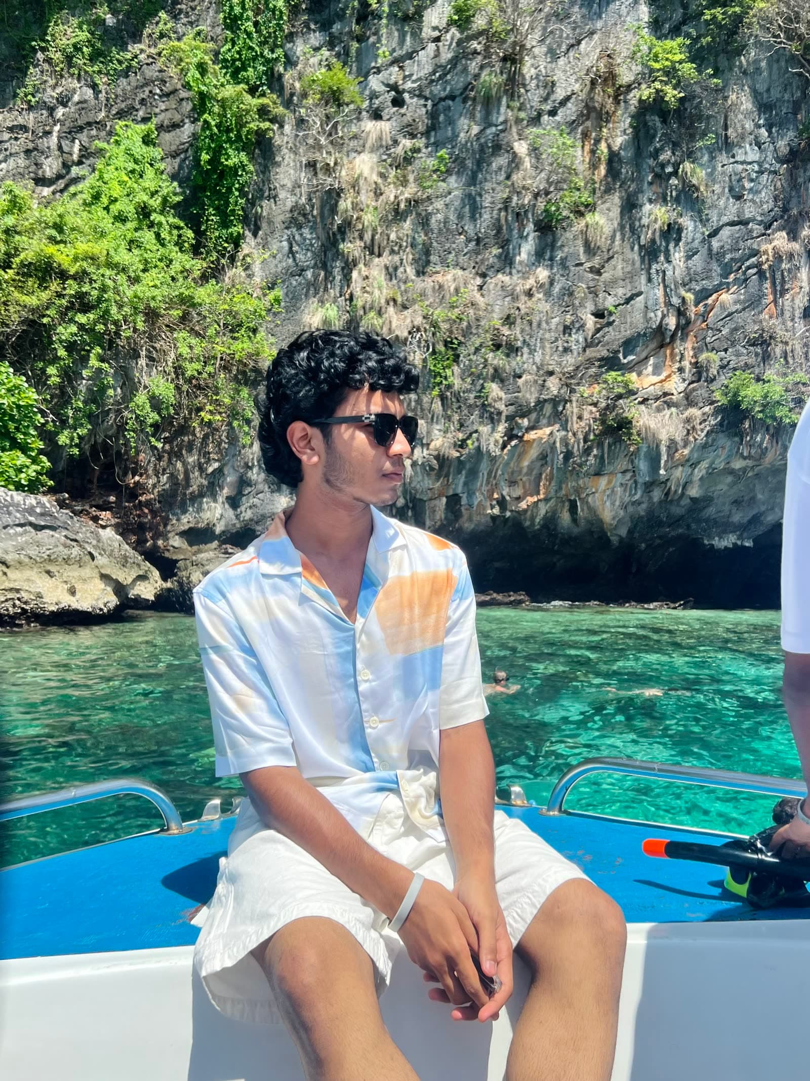 Mazin sitting on a speedboat bow at Phi Phi, Thailand, limestone cliffs and emerald water behind him